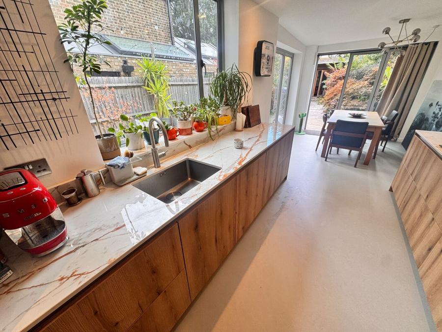 Sink set into the Dekton worktop beneath the window, with the dining space visible beyond