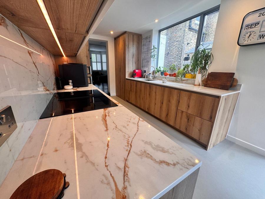 Close view of the veined Dekton worktop and matching splashback, lit from under the wall units