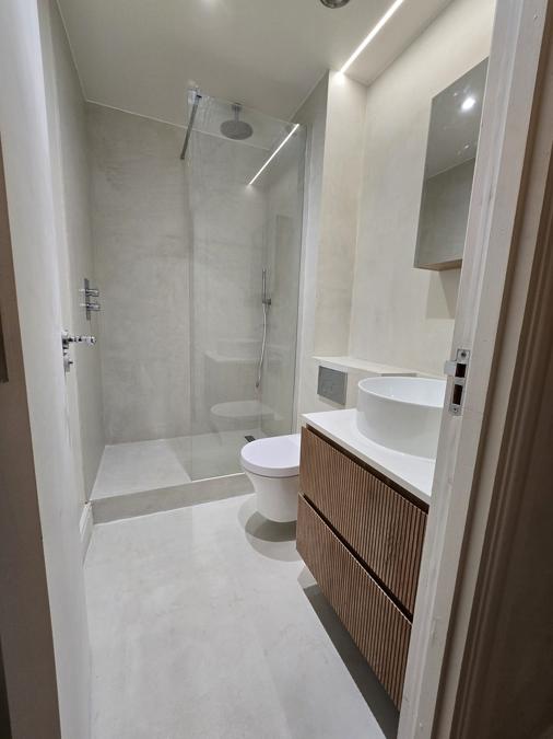 Bathroom in the Marylebone flat with wood slat panelling and a round countertop basin