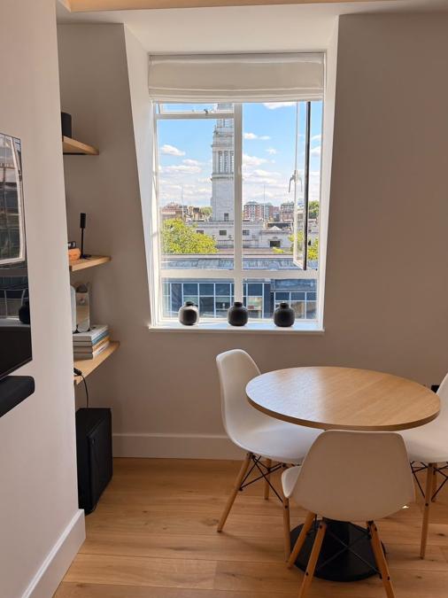 Dining area in the Marylebone flat set beside the window, with a round table and a view over the city