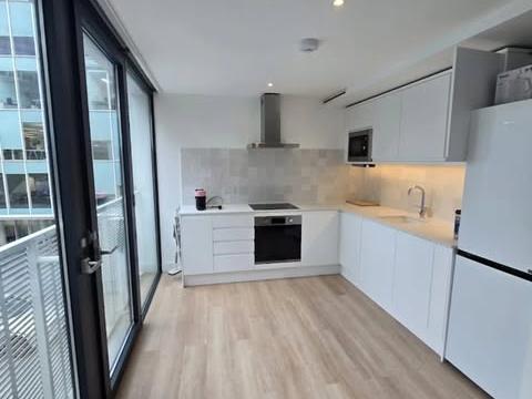 Battersea kitchen renovation with white cabinetry, wood flooring and balcony doors