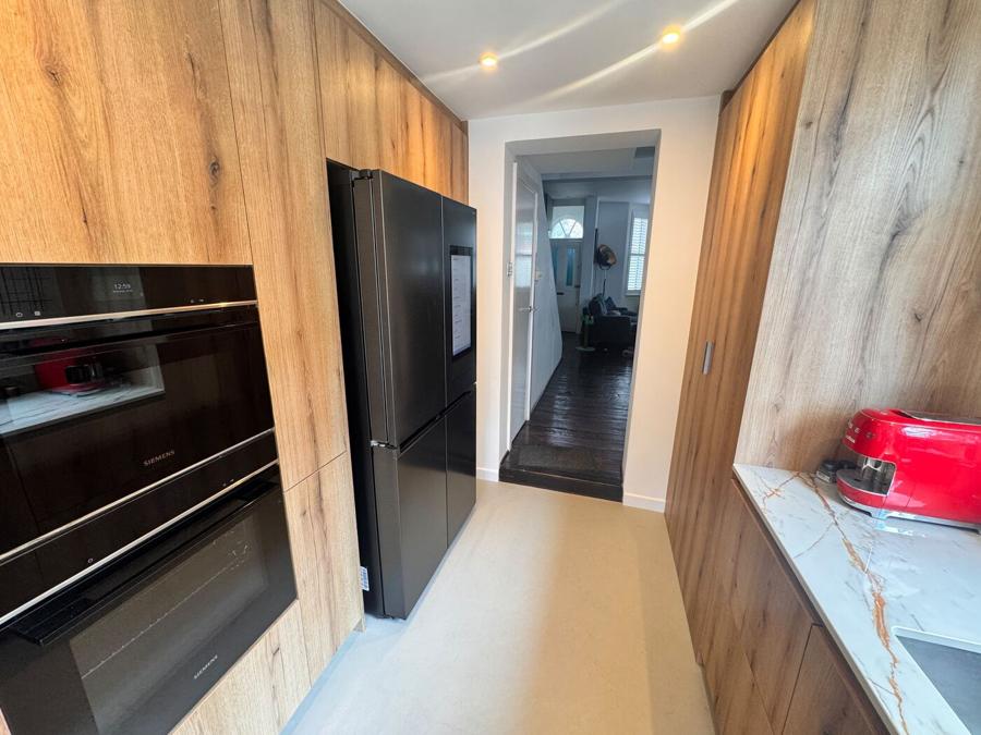 Integrated Siemens ovens and a tall fridge freezer built into the wood cabinetry run