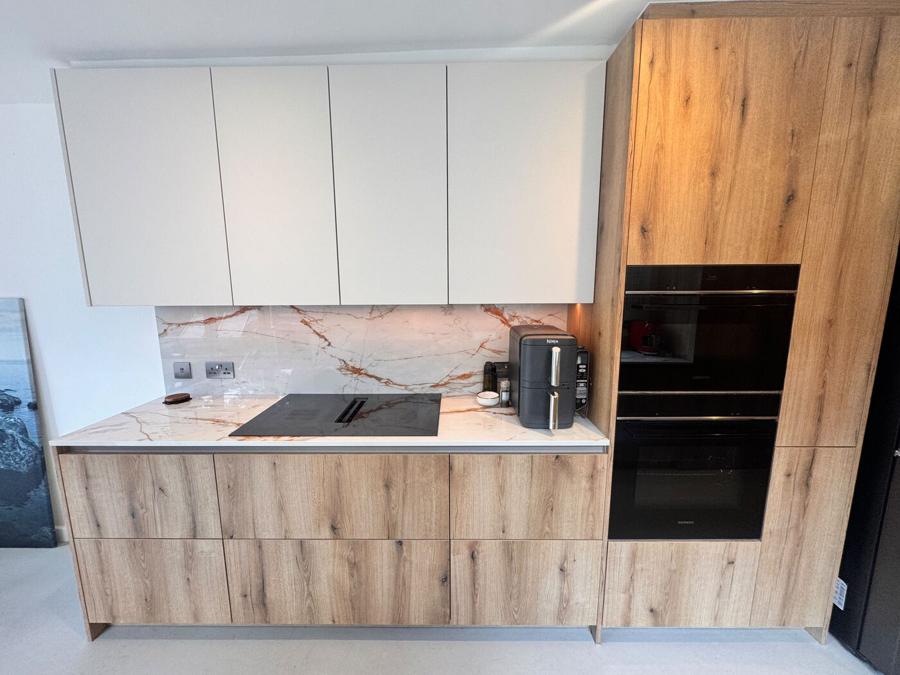 Hob run in the Bermondsey kitchen with white wall units, Dekton splashback and integrated Siemens ovens alongside