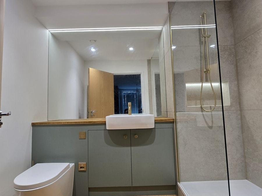 Dalston en-suite bathroom with sage green vanity, glass shower screen and brushed brass fittings