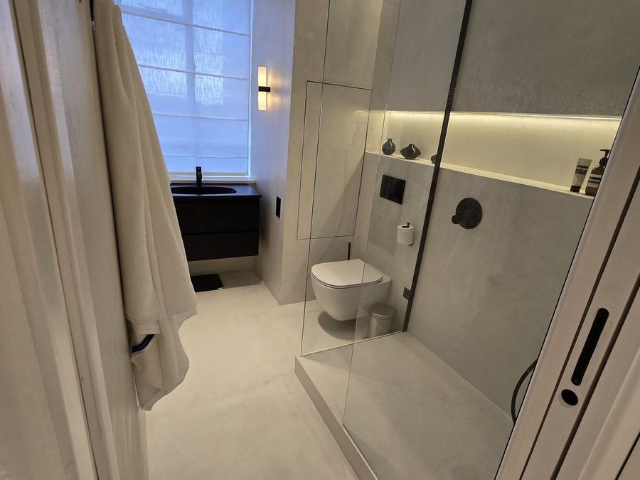 Bathroom finished in microcement with a glass shower screen and few visible joints