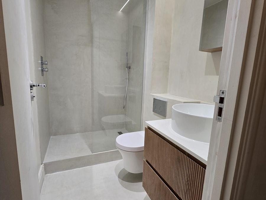 Bathroom in the Marylebone flat with wood slat panelling and a round countertop basin