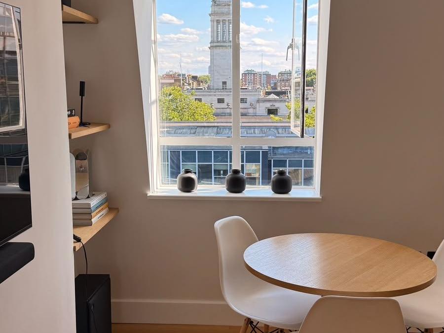 Dining area in the Marylebone flat set beside the window, with a round table and a view over the city