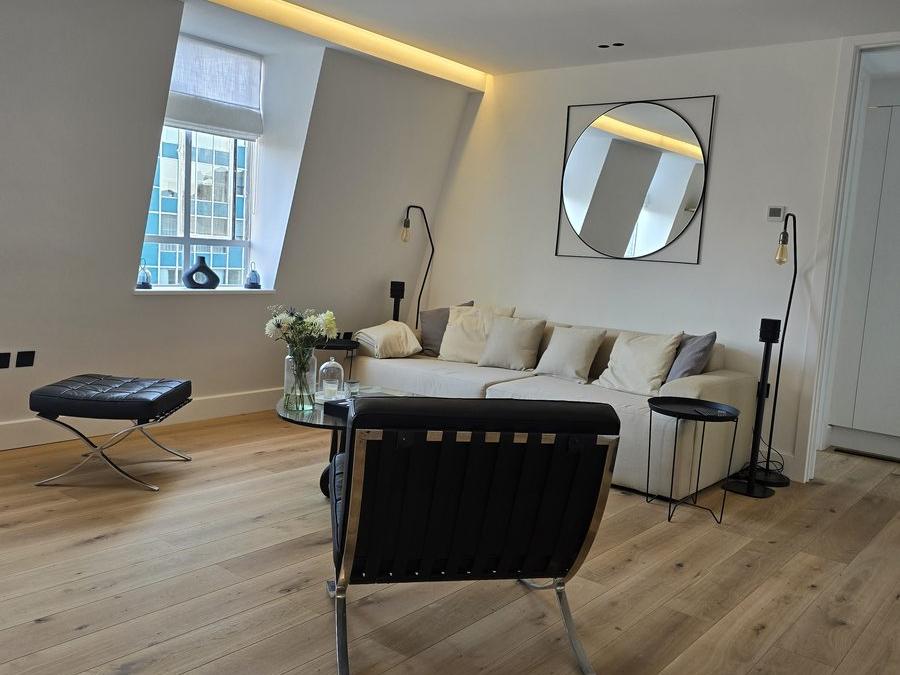 Living area of the Marylebone flat with engineered flooring, integrated lighting and a seating area