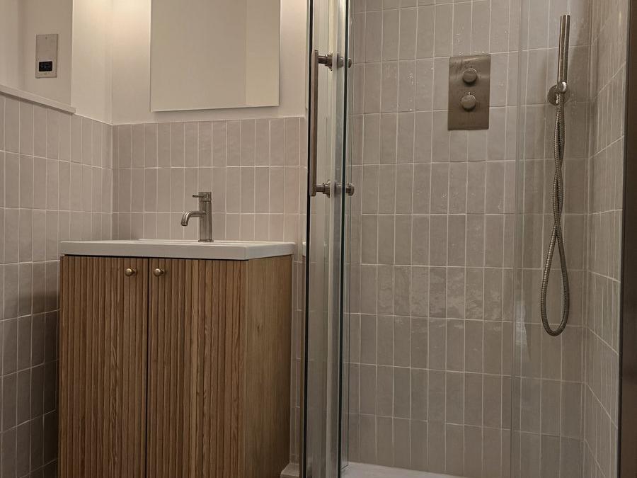 Rotherhithe bathroom with grey tiling, curved shower enclosure and oak vanity